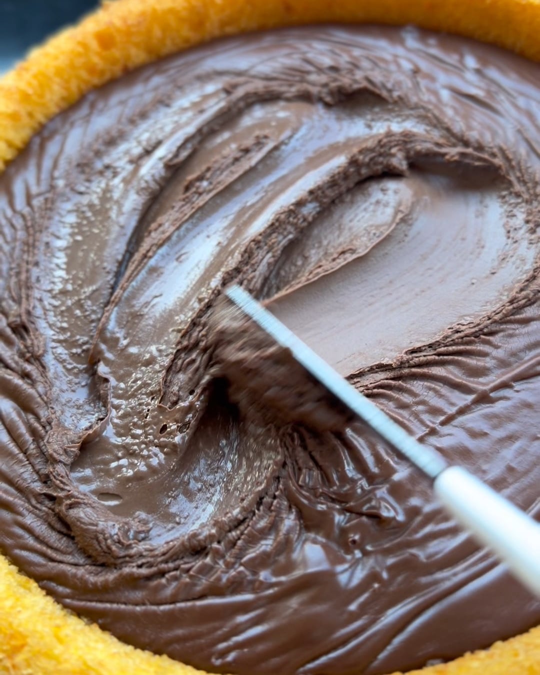Cobertura de chocolate sendo espalhada no bolo